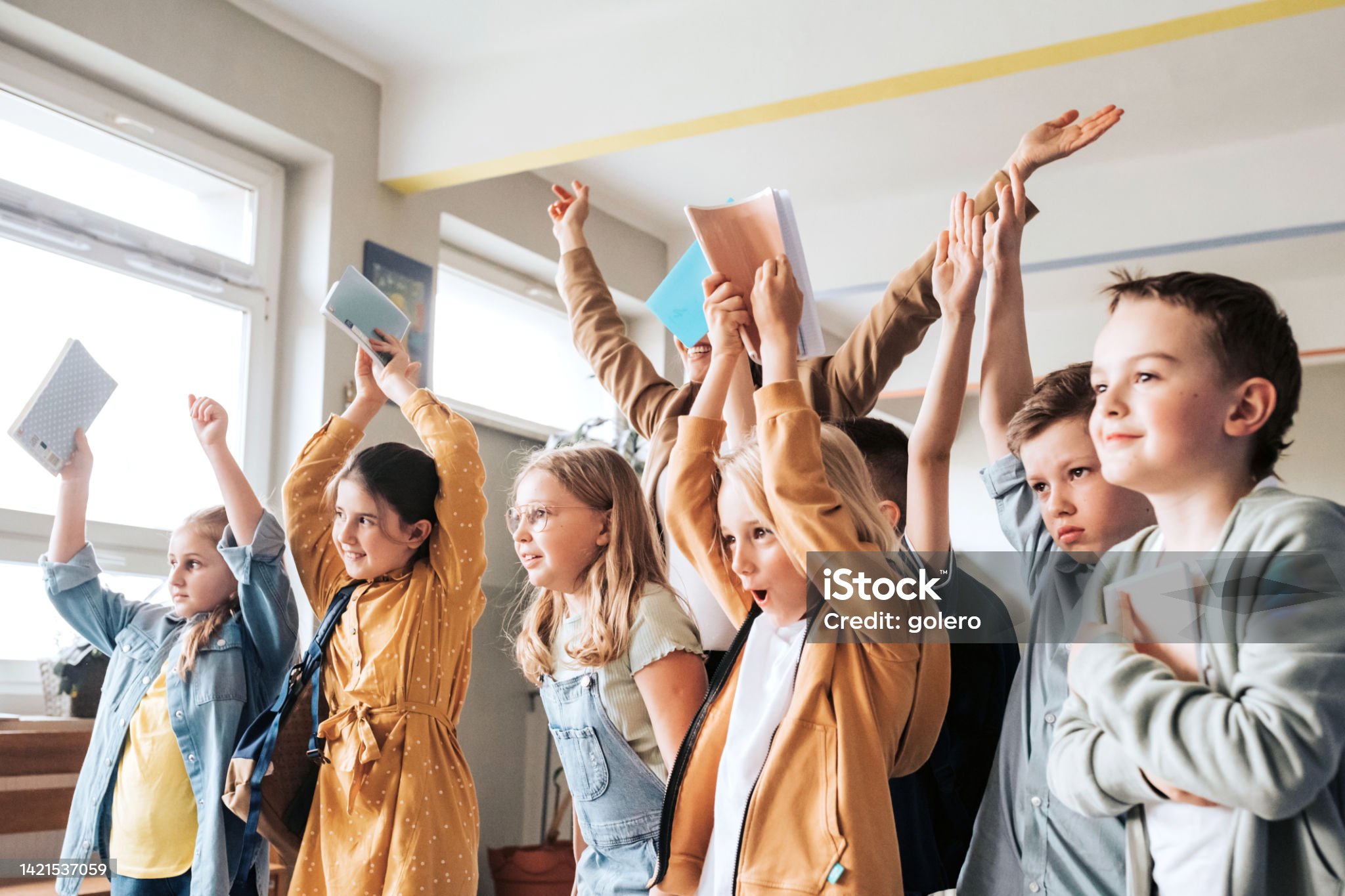 Schülerinnen und Schüler heben im Unterricht die Hände